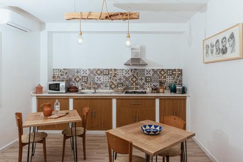 una cucina con tavolo e due tavoli e sedie di Domo Amsicora - Affittacamere - By Faendho a Porto Torres