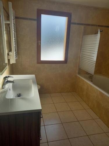 La salle de bains est pourvue d'un lavabo, d'une fenêtre et d'une baignoire. dans l'établissement Entre Lacs et Montagnes, à Traize