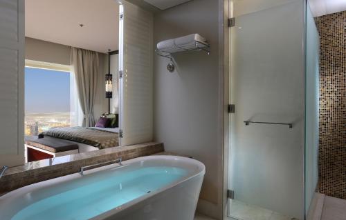 a white bath tub sitting next to a white sink at The Tower Plaza Hotel Dubai in Dubai