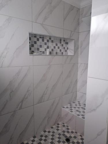 a bathroom with a shower with a black and white tiles at National Lodge in Benoni