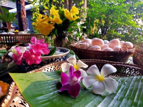 a table with baskets of eggs and flowers on it at Metha Country View Homestay Singburi in Ban Kho Sai