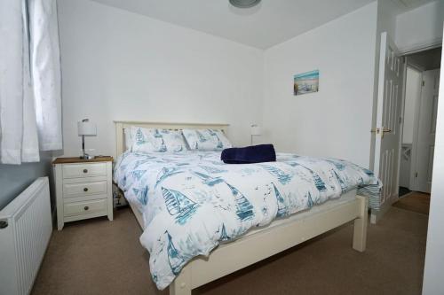 a bedroom with a bed with a blue and white comforter at The Coach House near Swanpool, Falmouth, Cornwall. in Falmouth