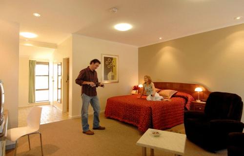 a man standing in a room with a bed and a woman at McLaren Vale Motel & Apartments in McLaren Vale