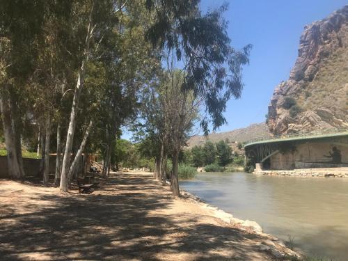 a road next to a river with trees and a bridge at Casa Ramoncico. Finca el Campillo in Blanca