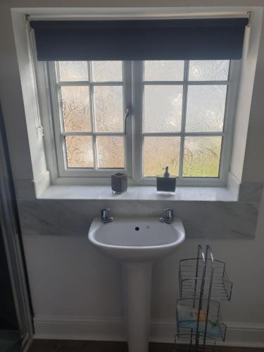 a white sink under a window in a bathroom at Greenacres in Kelsale