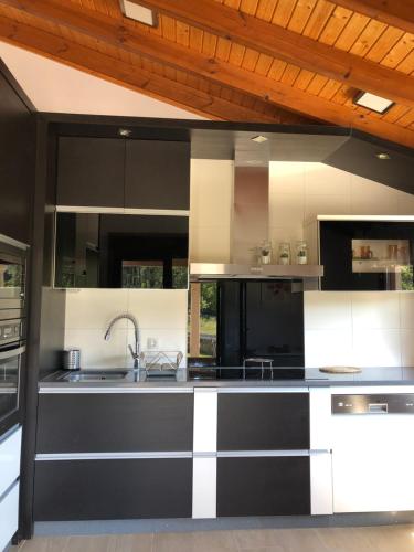 a kitchen with black and white cabinets and a sink at Pedra Moura Casa Rural in Gondomar