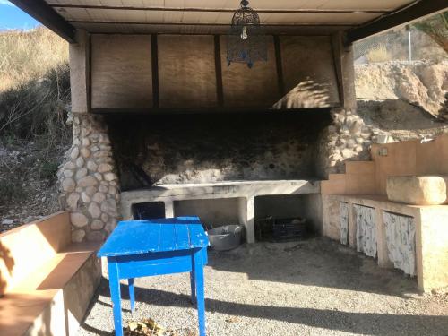 a blue table in front of a stone fireplace at Casa Ramoncico. Finca el Campillo in Blanca