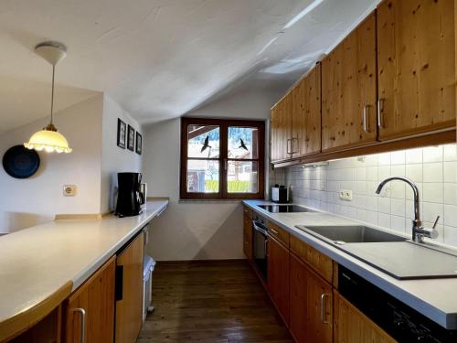 a kitchen with wooden cabinets and a sink and a window at Landhaus Bergidyll - Ferienwohnung Kapellenblick in Bolsterlang