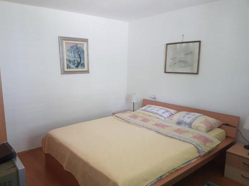 a bed in a bedroom with two pictures on the wall at Pržić House in Negotin