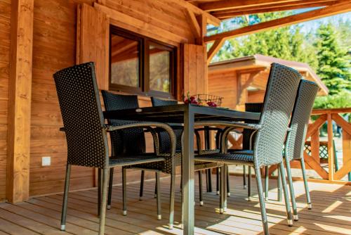 einen Tisch und Stühle auf dem Deck einer Hütte in der Unterkunft Woda i Las in Jeżewo