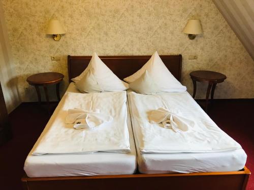 two beds with white sheets and shoes on them at Schlosshotel Stecklenberg in Thale