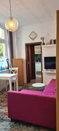 ein Wohnzimmer mit einem lila Sofa und einem Tisch in der Unterkunft Büdchen am Rathaus-Parkplatz-Bett und Schlafcouch-EG-NETFLIX- in Oberhausen