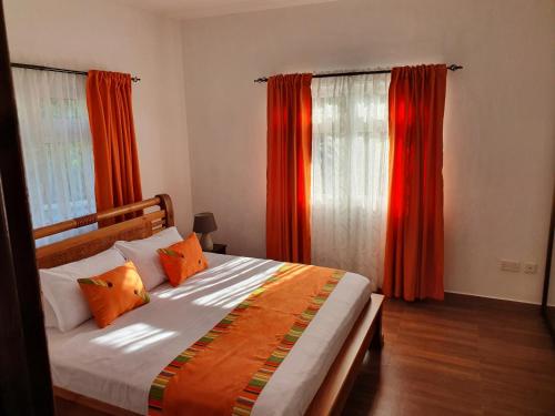 a bedroom with a bed with orange curtains at Grace Self Catering in Anse aux Pins