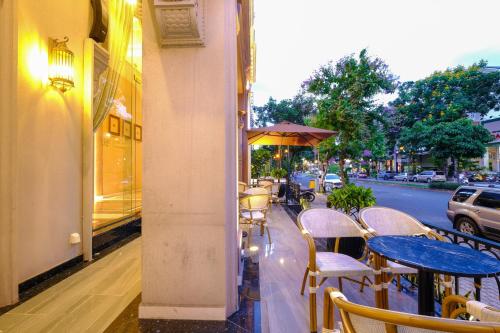 an outdoor cafe with tables and chairs and an umbrella at Golden Tree Hotel & Apartment in Ho Chi Minh City