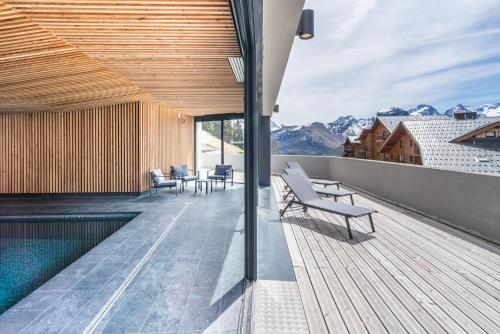 a balcony with chairs and a swimming pool on a building at Vacancéole - Les Ecrins d'Auris in Auris
