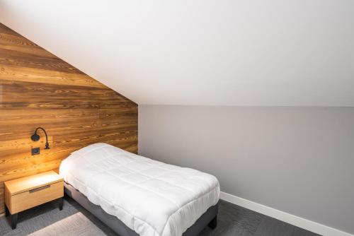 a bedroom with a bed and a wooden wall at Vacancéole - Les Ecrins d'Auris in Auris