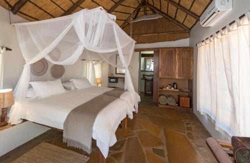 een slaapkamer met een hemelbed bij Onguma Forest Camp in Namutoni