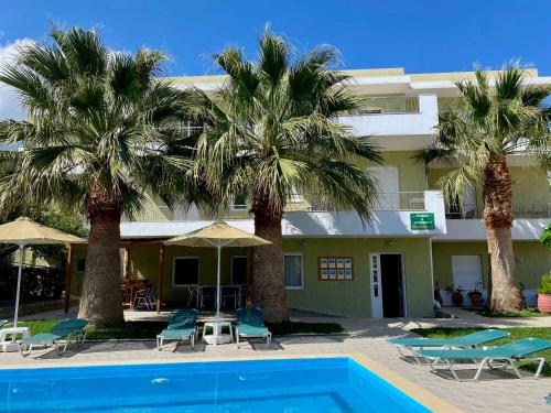 a hotel with palm trees and a swimming pool at Manolis Apartments plakias in Plakias