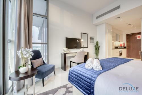 a bedroom with a blue bed and a desk and chair at Sunlit Studio at Golf Promenade 2A DAMAC Hills By Deluxe Holiday Homes in Dubai