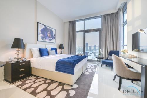 a bedroom with a large bed and a desk and a desk at Sunlit Studio at Golf Promenade 2A DAMAC Hills By Deluxe Holiday Homes in Dubai