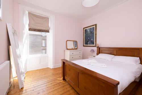 a bedroom with a large white bed and a window at JOIVY Gorgeous 1-bed flat with a shared garden in Edinburgh