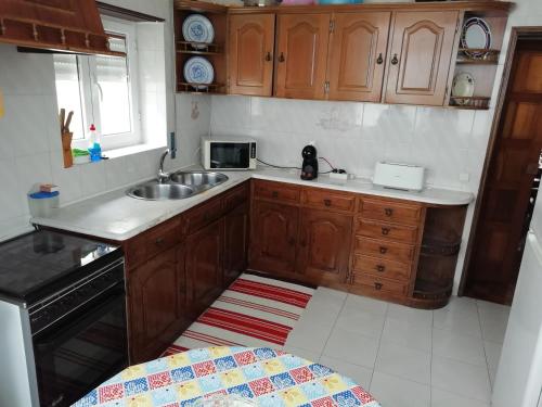 cocina con armarios de madera, fregadero y microondas en Casas da Cacilda, en Nazaré