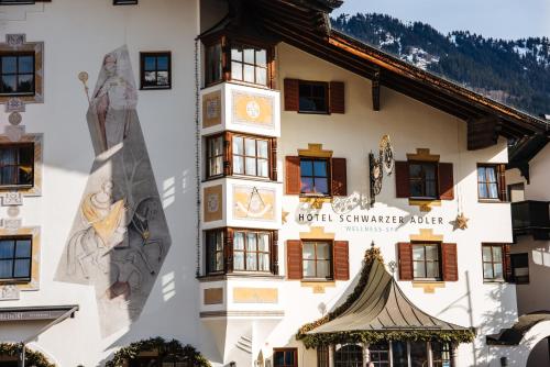 a building with a clock on the side of it at Schwarzer Adler Kitzbühel - Adults Only in Kitzbühel