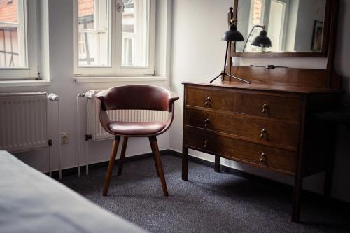 a bedroom with a dresser and a chair next to a dresser at Magni Boutique Hotel in Braunschweig