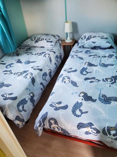 Un dormitorio con una cama con una colcha azul y blanca. en Mobil home chez l habitants, en Saint-Jean-de-Monts