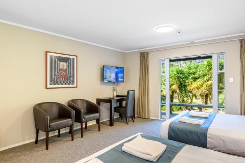 a hotel room with two beds and a desk at Northridge Golf Resort in Orewa