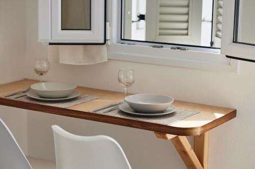 a table with two bowls and wine glasses on it at Kanala Studios in Kithnos