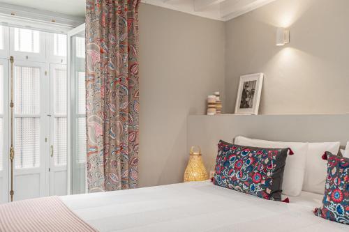 a bedroom with a bed and a window with curtains at Art Suites by Casa de Indias in El Puerto de Santa María
