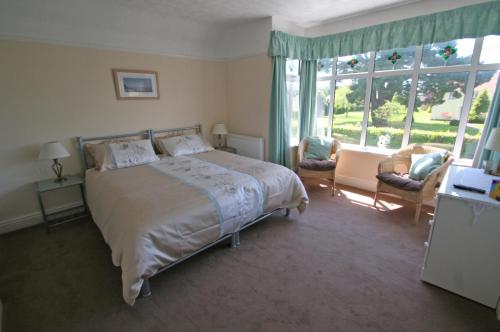 a bedroom with a bed and a large window at Beech Lodge Guest House in New Milton