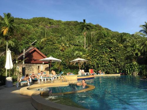 a pool at a resort with people in the water at Tanouy Garden in Baan Khai