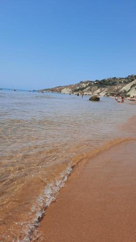 a beach with the ocean and people in the water at Appartamento Porto Marina S G 2 in Licata