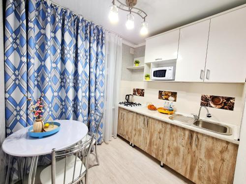 eine Küche mit einem Tisch und einer Arbeitsplatte in der Unterkunft Абсолютно новая квартира класса ЛЮКС in Taras