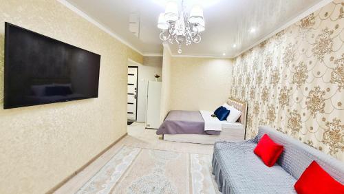 a bedroom with a bed and a tv on the wall at Абсолютно новая квартира класса ЛЮКС in Taraz