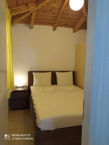 a bedroom with a white bed with a wooden ceiling at camping hydraswave bungalow caravan in Thermisía