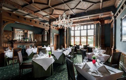 a restaurant with white tables and chairs and a chandelier at Woodlands Park Hotel in Cobham
