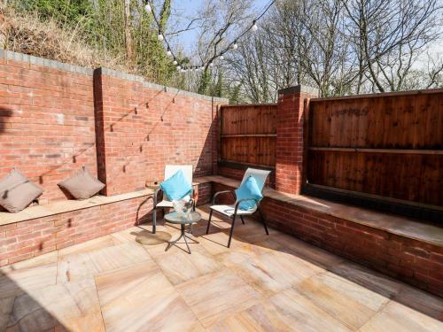 a patio with two chairs and a bench on a brick wall at Nant House in Wrexham