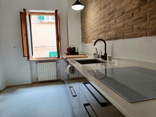 een keuken met een wastafel en een bakstenen muur bij I Capricci di Florian in Perugia