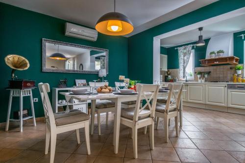 a kitchen with a table and chairs and a green wall at Villa Laura in Krnica
