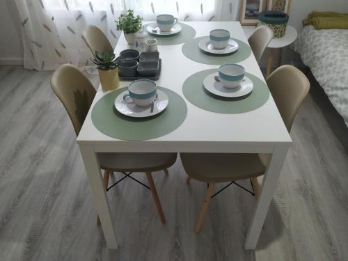 a white table with four chairs and cups and saucers at Piso Victoria in Sant Feliu de Guíxols