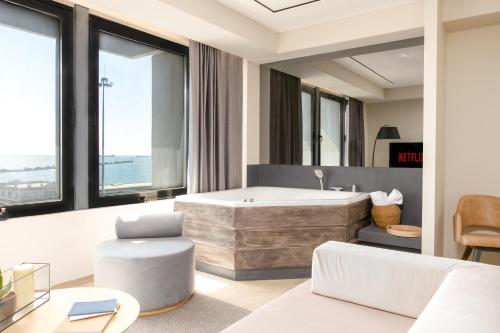 a bathroom with a tub and a chair and a couch at Sea & the City in Thessaloniki