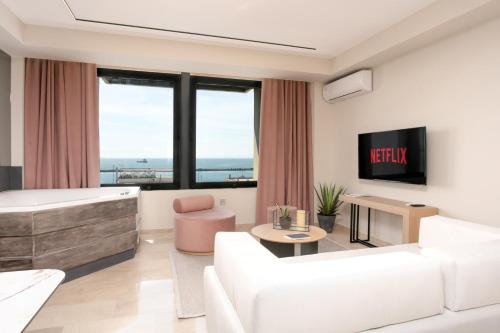 a living room with white furniture and a tv at Sea & the City in Thessaloniki
