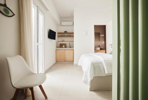 a bedroom with a white bed and a white chair at Kanala Studios in Kithnos