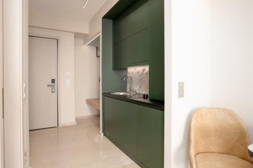 a kitchen with green cabinets and a chair in a room at Sea & the City in Thessaloniki