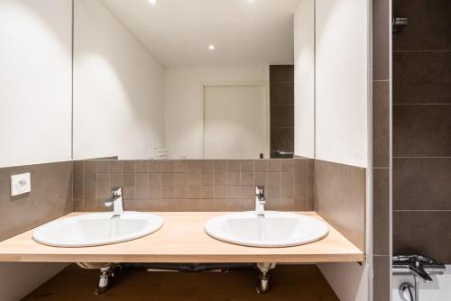 a bathroom with two sinks and a mirror at Vacancéole - Les Ecrins d'Auris in Auris