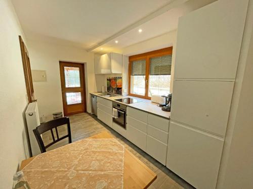 a kitchen with white cabinets and a table and a refrigerator at Fewo Ziemer 2 in Piding