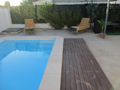 a swimming pool with two chairs and an umbrella at Casa con piscina privada en barrio tranquilo in Castelló d'Empúries